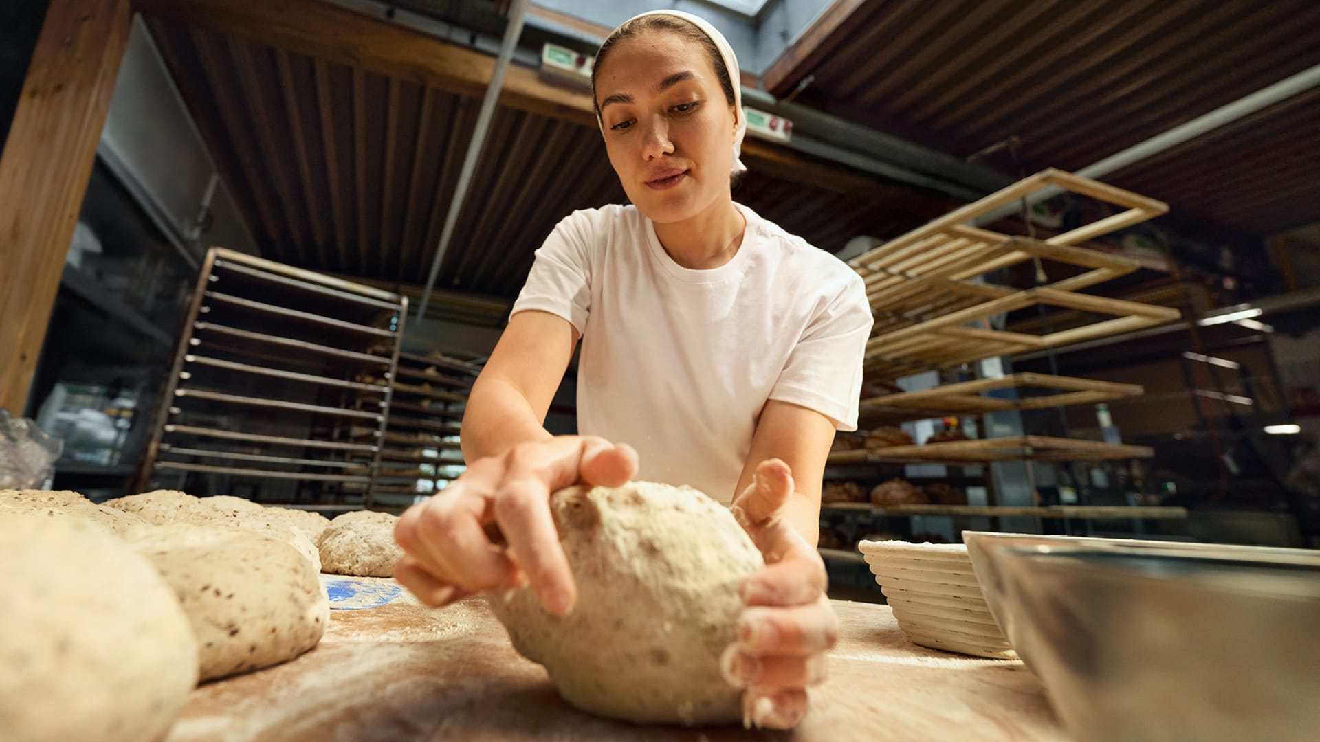 Eine Bäckerin knetet konzentriert einen Brotteig