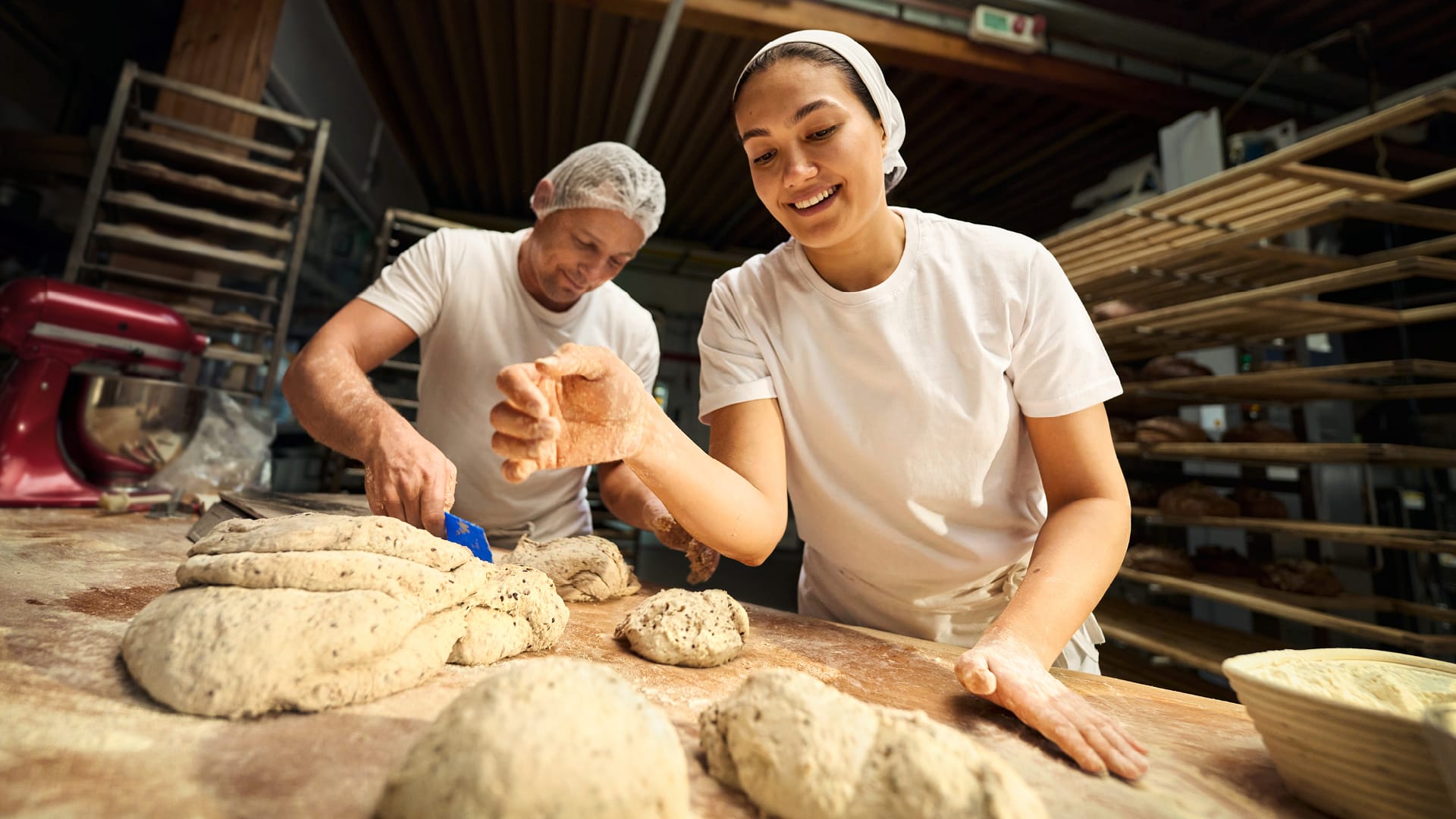 Ein Bäcker und eine Bäckerin beim Teig kneten