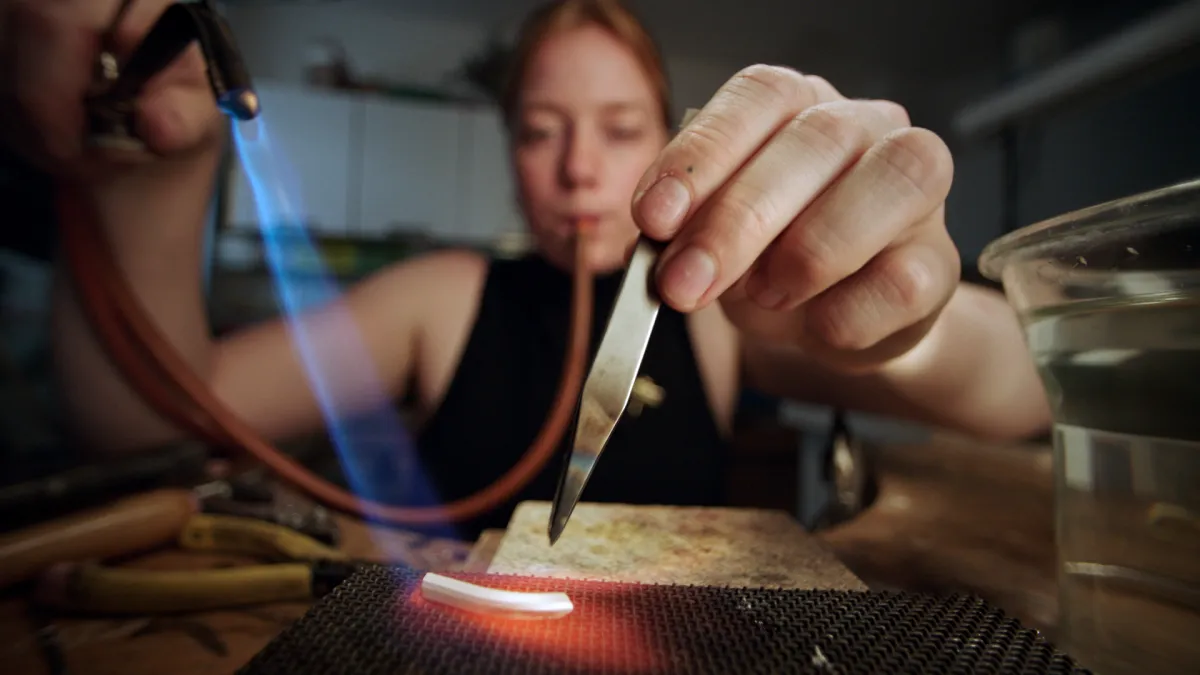 Goldschmiedin Hereza erhitzt ein Stück Metall