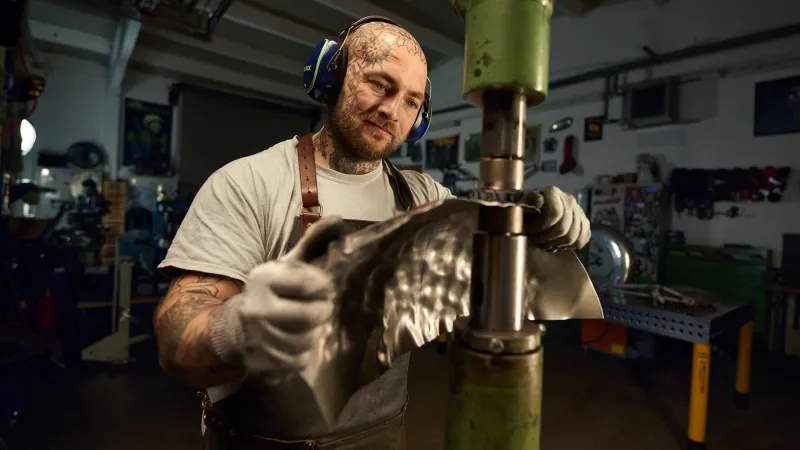 Ein Handwerker klopft Blech mit einer Maschine