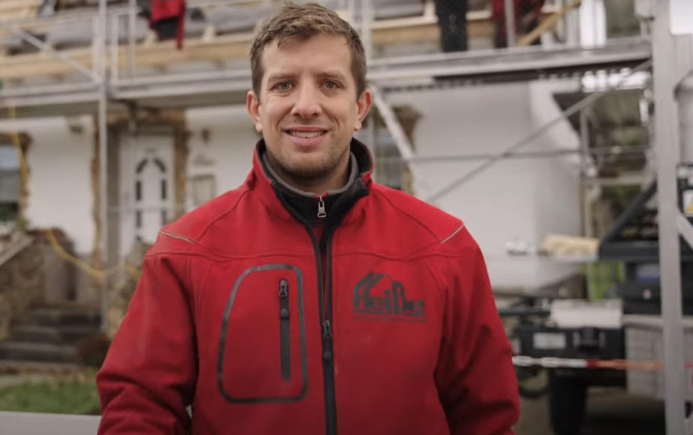 Mann in roter Jacke schaut in die Kamera