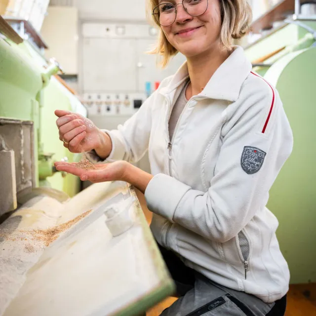 Müllerin in Berufsbekleidung neben Maschinen